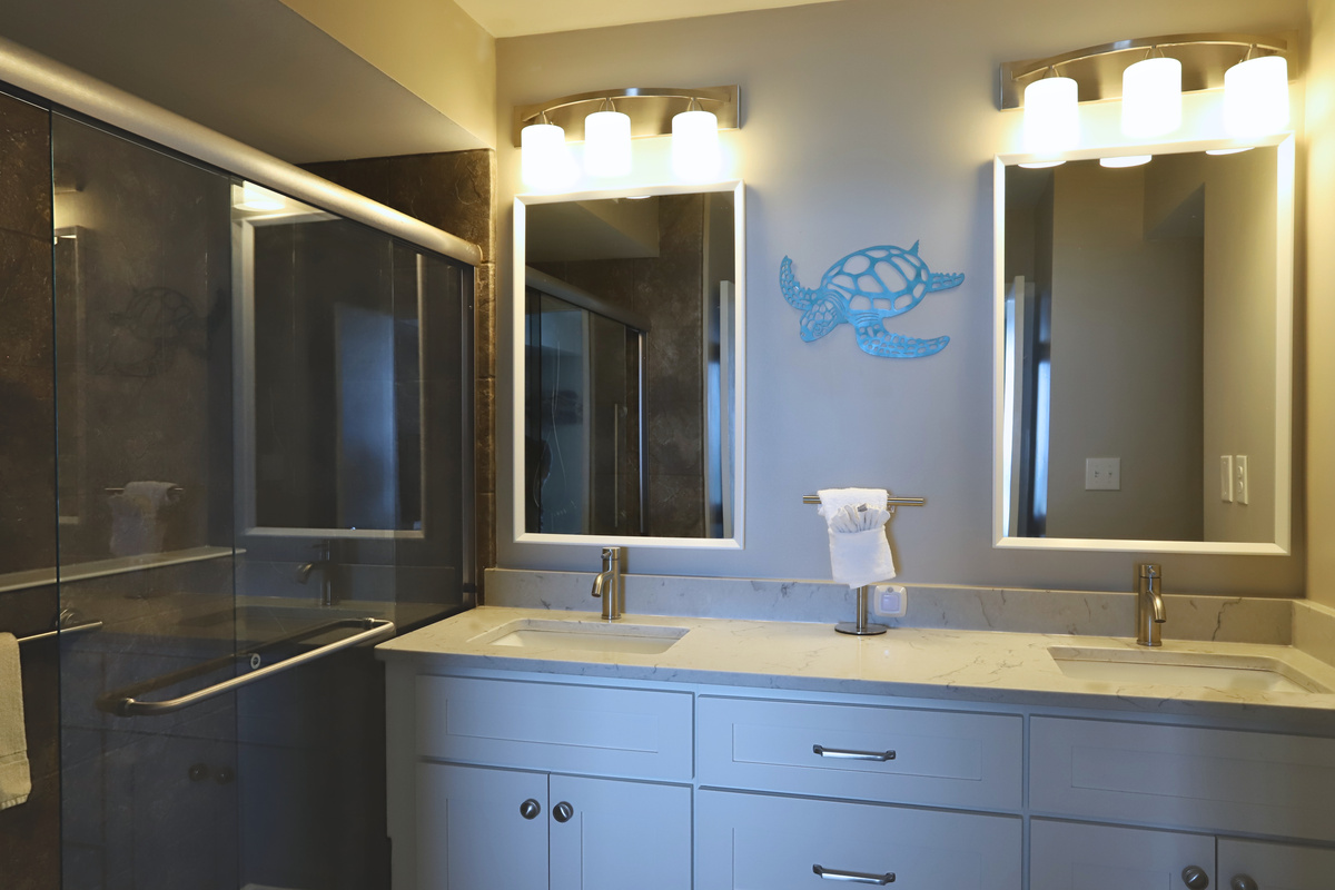 A spacious bathroom with double sinks and mirrors, an oversized white cabinet, and a roomy walk in shower—blending elegance and practicality for a serene, luxurious experience.