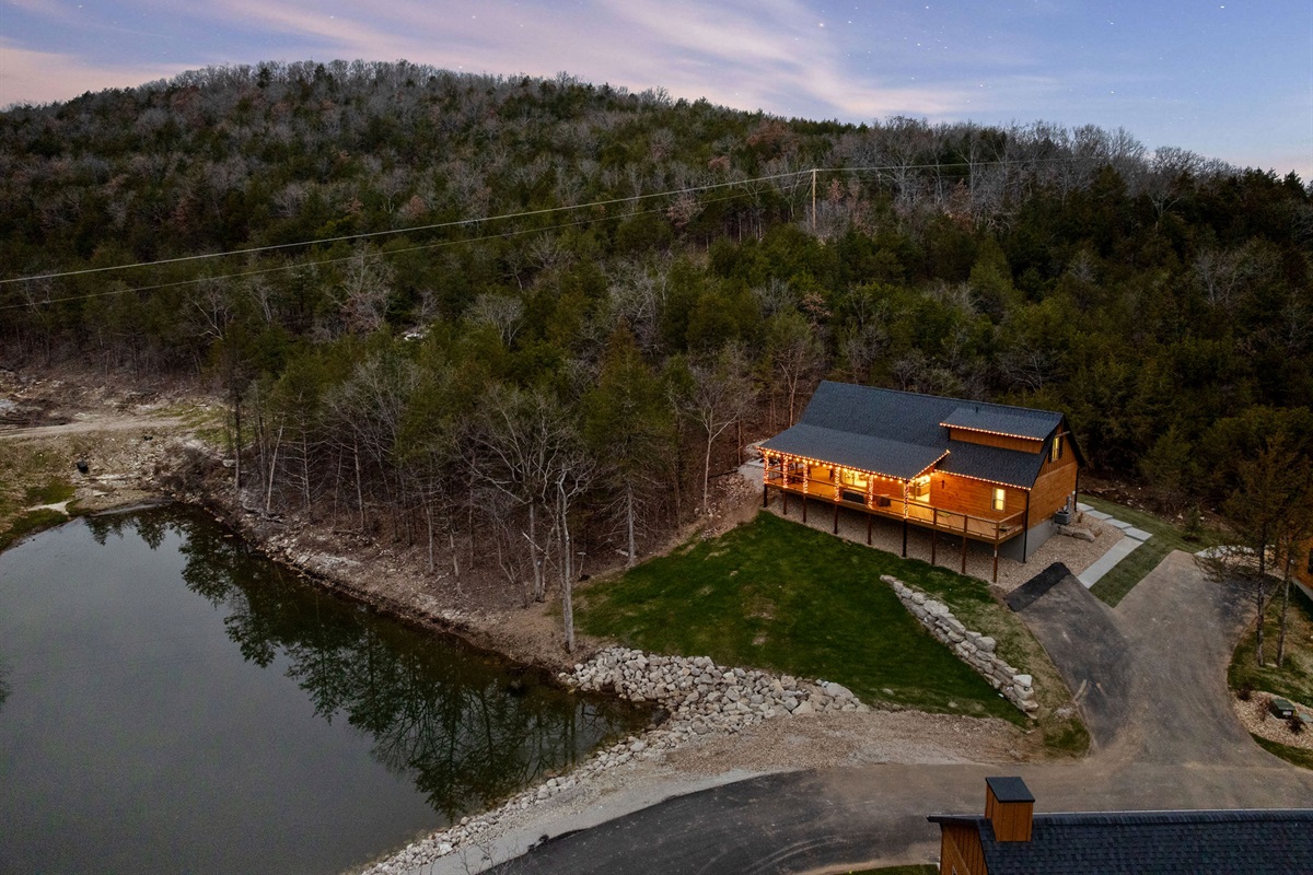 Scenic aerial view of the cabin set near the water and trees.