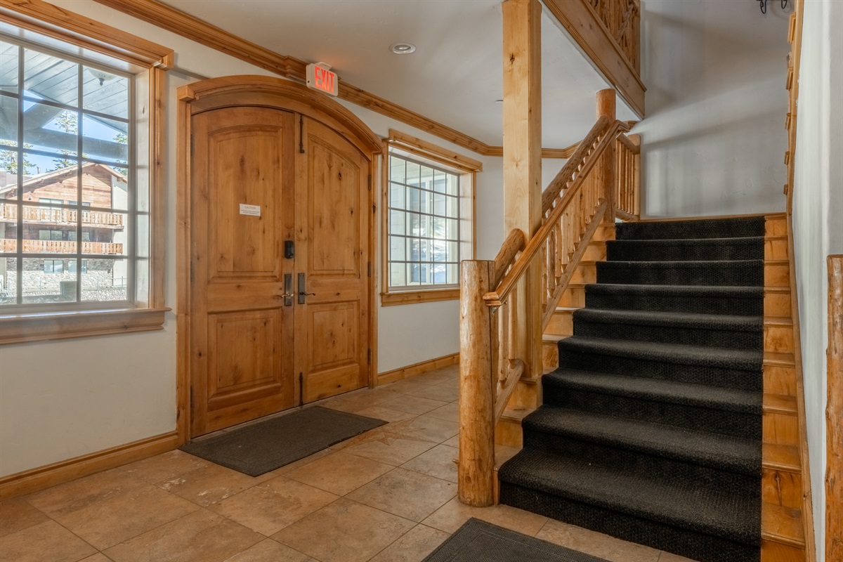 Wide, open log stairwell connects all shared interior spaces like garage, ski storage, and foyers and leads to each condo.