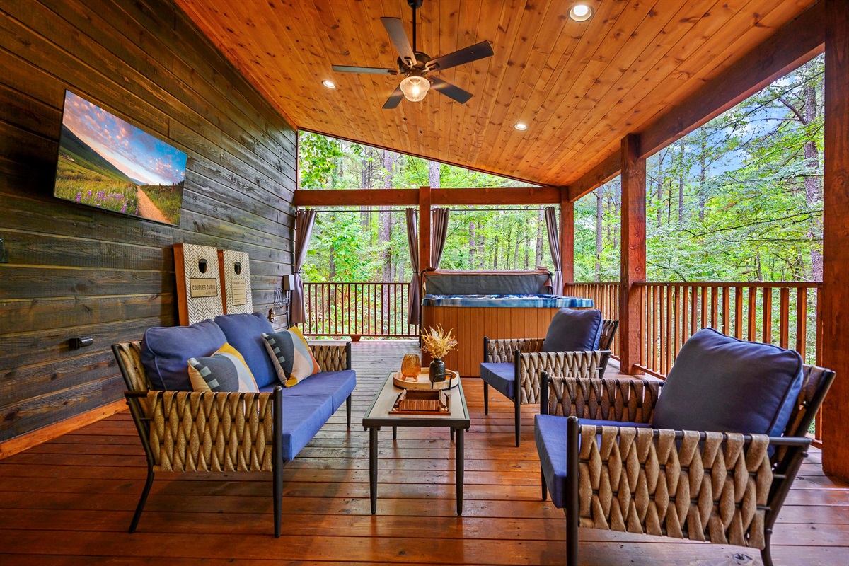 Large covered deck with cozy seating and TV on deck.