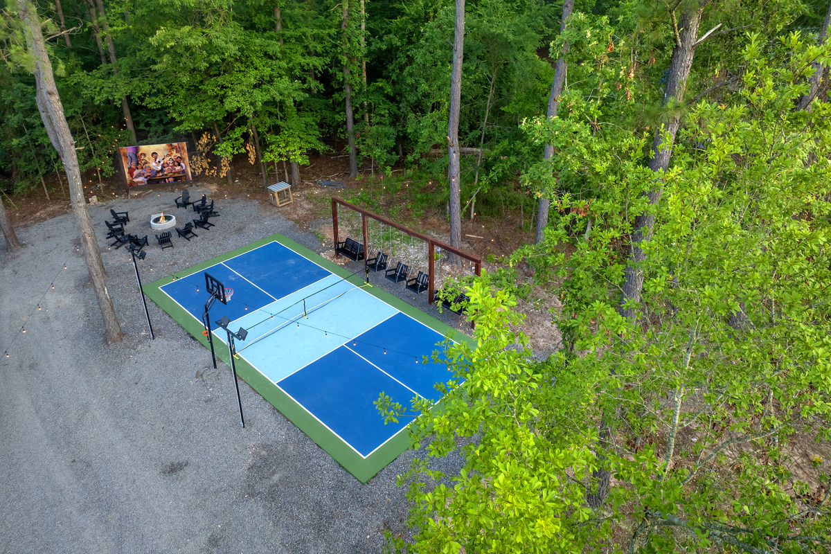 Private pickleball + basketball court surrounded by towering pines, with spectator swings, a fire pit & outdoor cinema just steps away at the firepit. Play all day, movie night after dark.