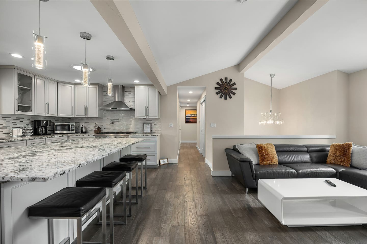 “A beautifully designed open kitchen and living area with modern décor, a large island, and comfortable seating, creating a welcoming and connected space.”