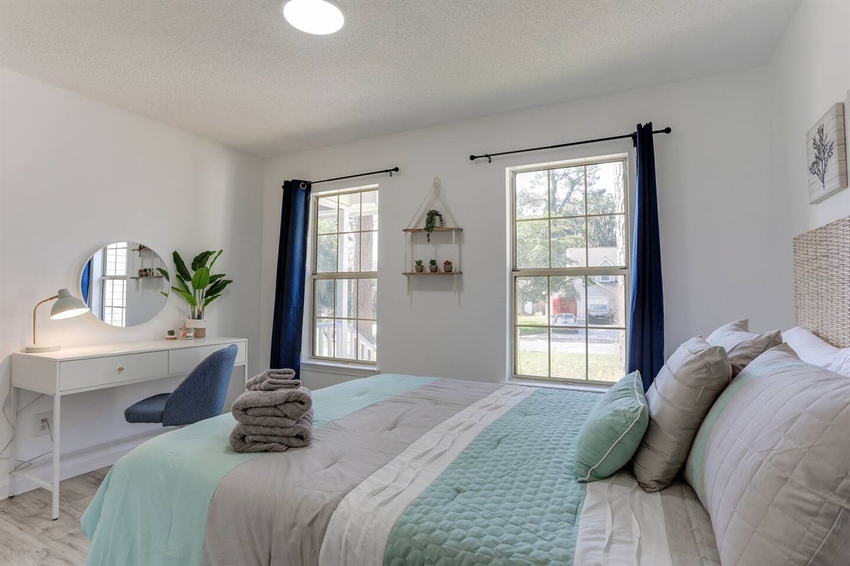 Bright and inviting, the second bedroom features a cozy queen bed, a convenient desk, and large windows that fill the space with natural sunlight.