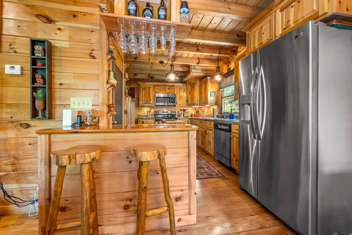 Rustic full kitchen with stainless steel appliances, handcrafted wood finishes, and a cozy breakfast bar.