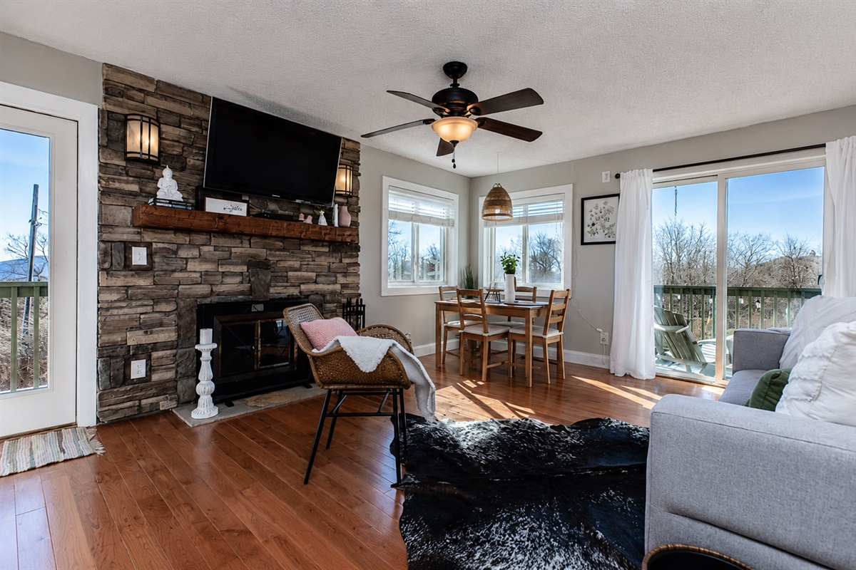 Cozy living room with wood burning fireplace and door leading to balcony. Open-concept living space—perfect for relaxing together