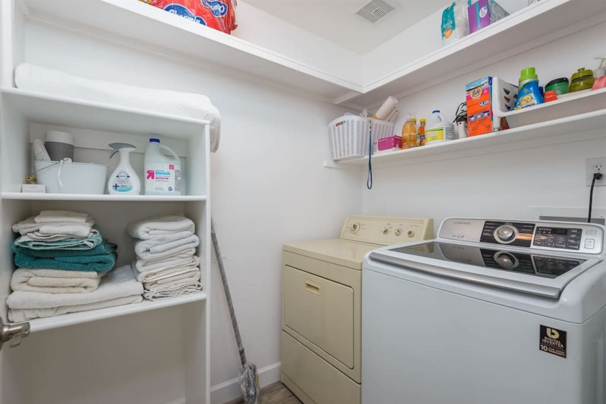 Laundry room with washer, dryer, extra towels, and supplies for guest use.
