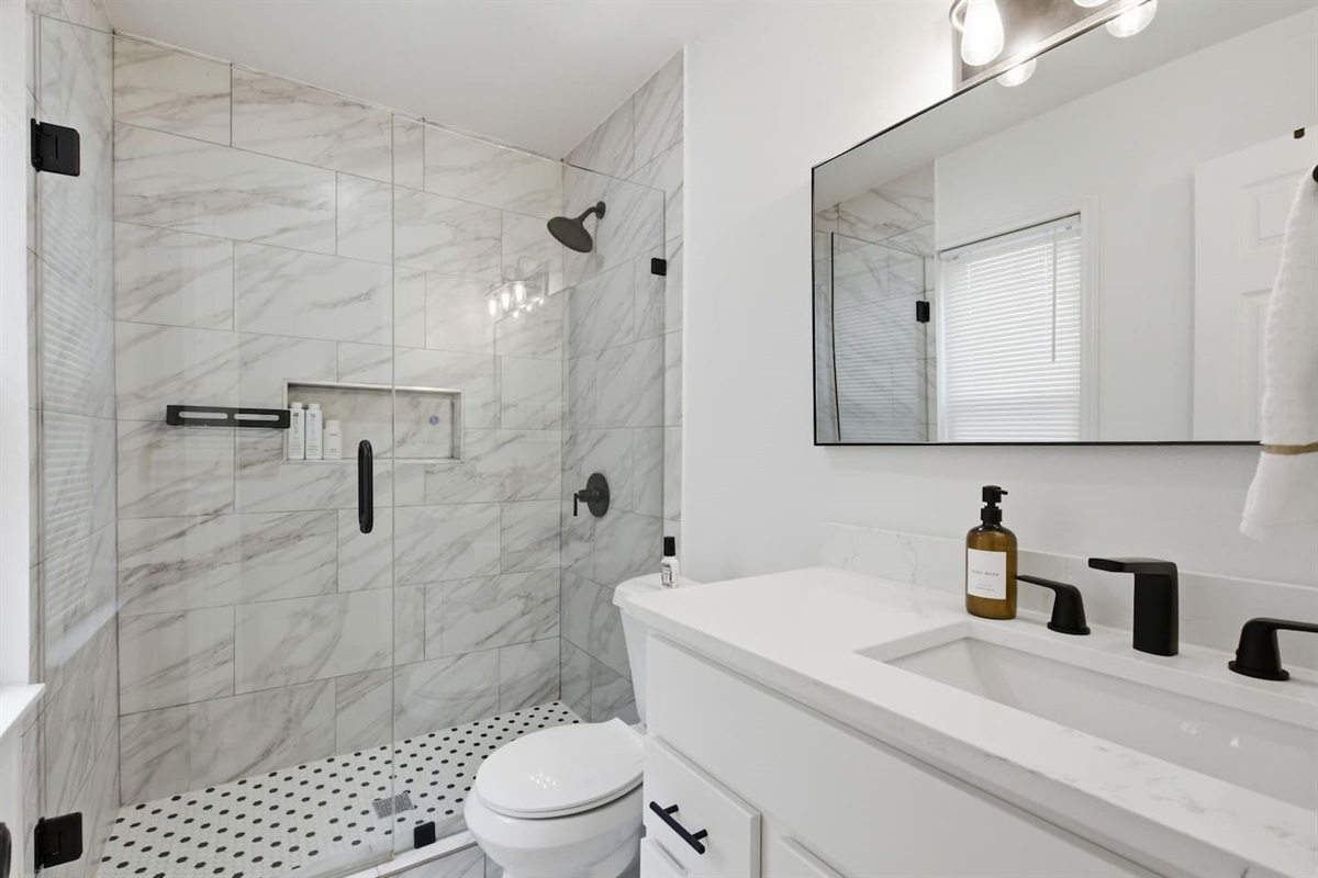 Stylish bathroom featuring walk-in shower, marble tile walls, modern fixtures, and sleek finishes.