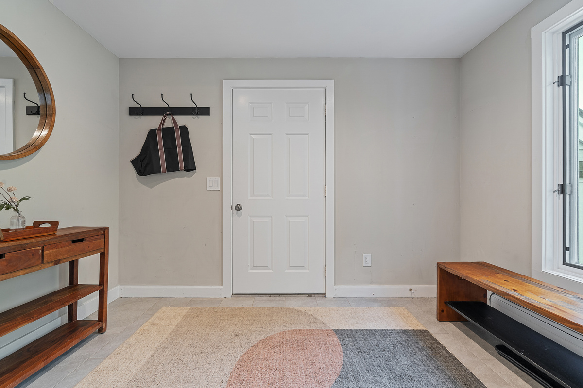 Mudroom entry with bench, hooks and tile flooring for ski boots and gear