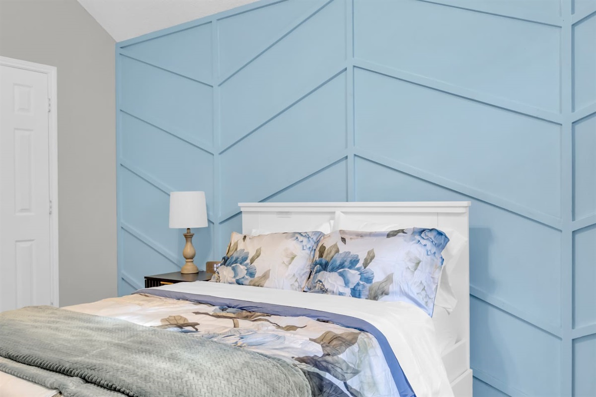 Well-appointed queen bedroom with blackout blinds, ceiling fan, high-speed Wi-Fi, modern décor, and cozy bedding designed for family and group stays.