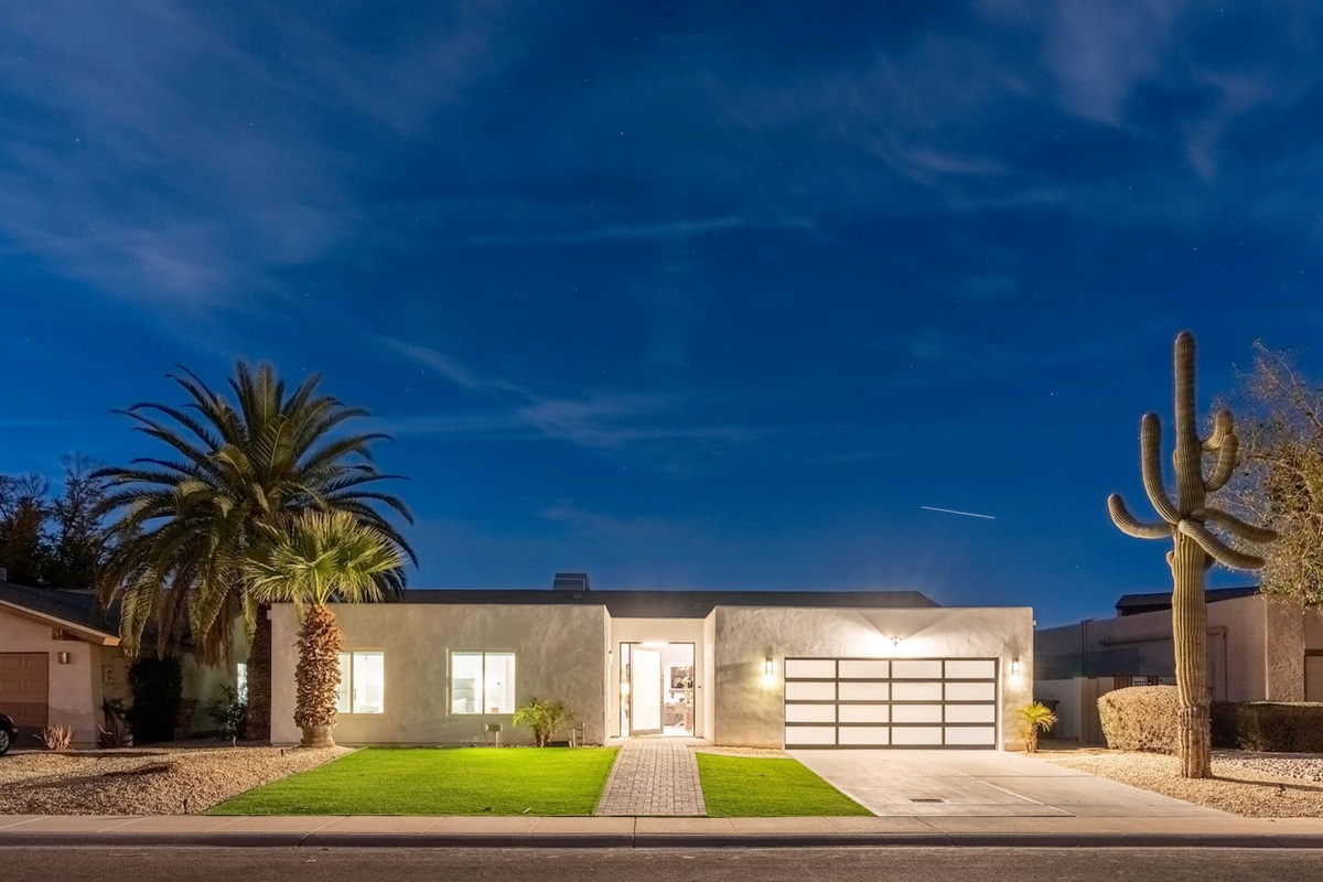 Elegant exterior lighting highlights the palm trees and architectural design.

