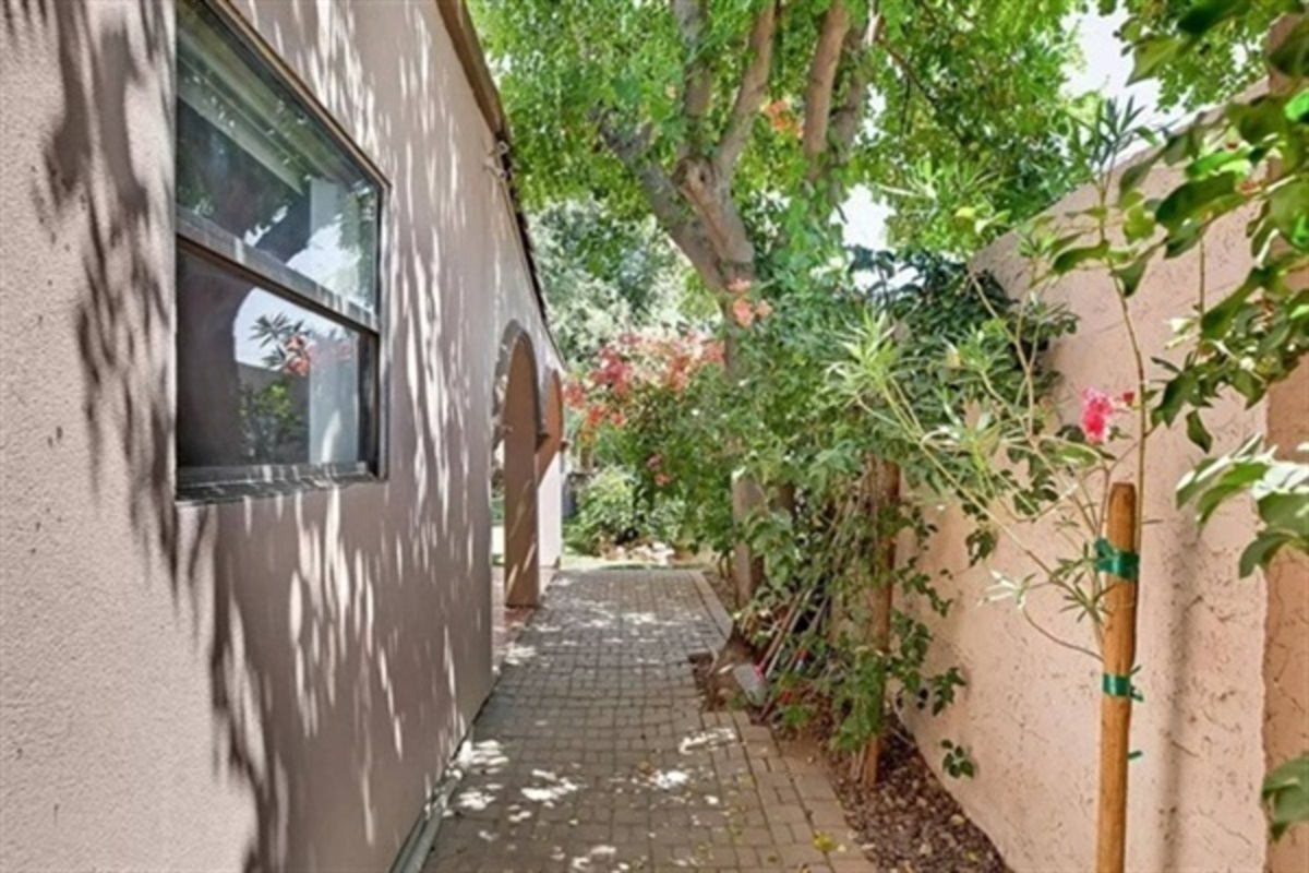 A quiet garden walkway lined with flowers and trees creates a private, peaceful passage through the heart of the home.