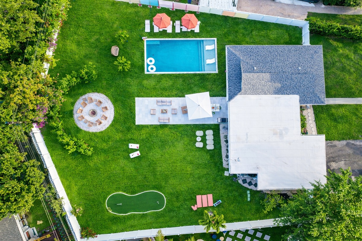 Private Palm Beach backyard with heated saltwater pool, fire pit, mini golf putting green, and outdoor lounge seating.