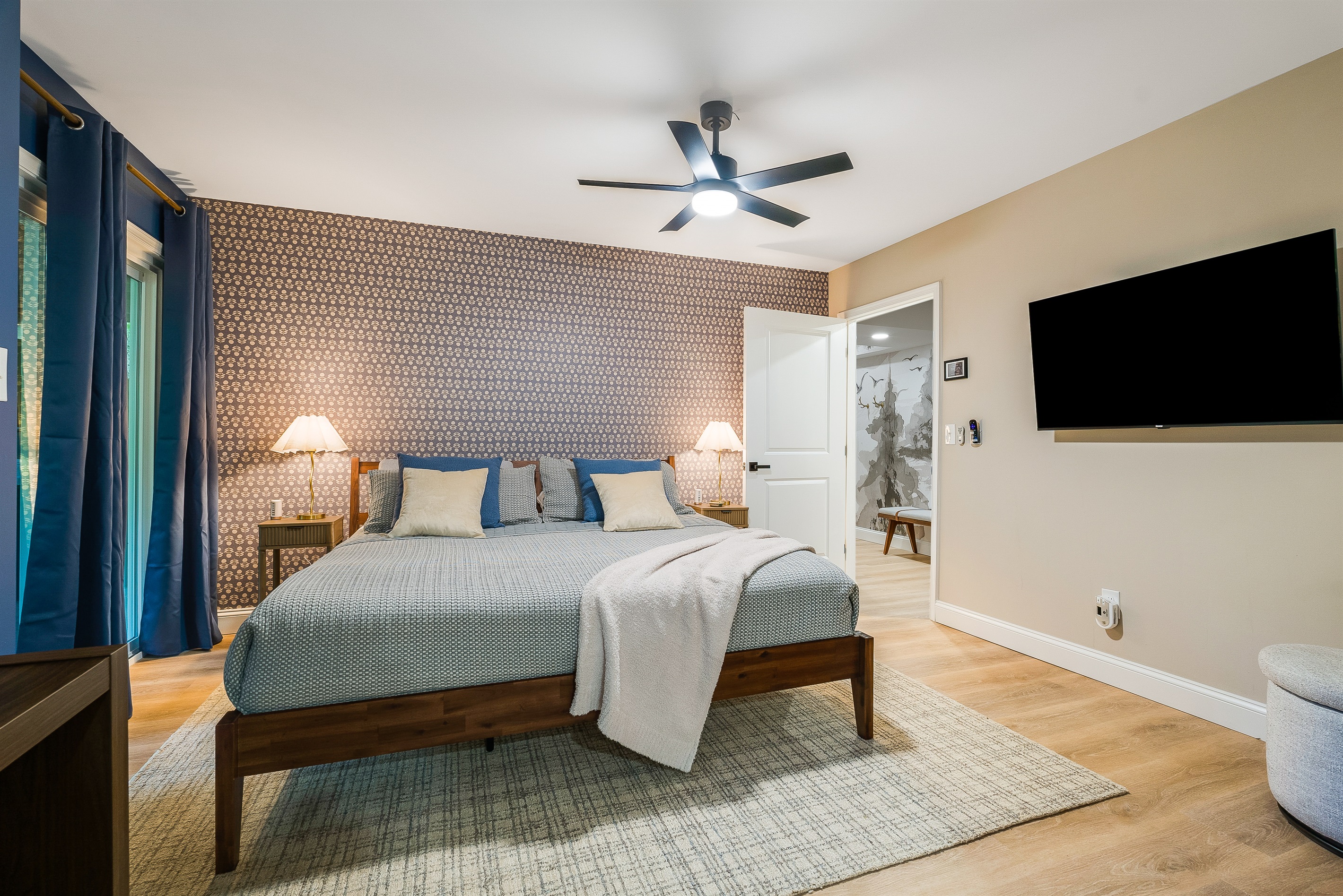 A stylish king bedroom with a patterned accent wall, crisp bedding, and rich blue curtains. Perfect for couples or grandparents in the group who want a little extra privacy while still staying close to the action.