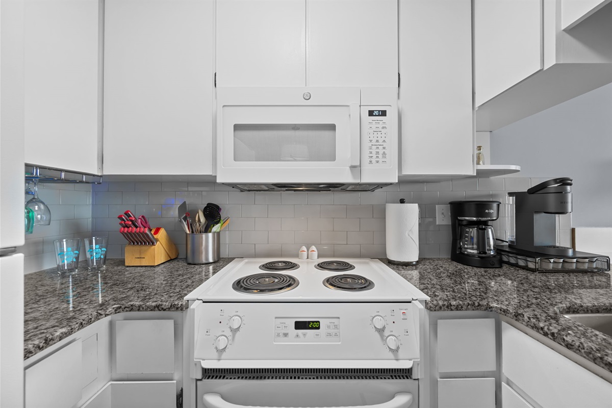 Clean, functional cooking space with electric range, microwave, and thoughtfully stocked essentials
