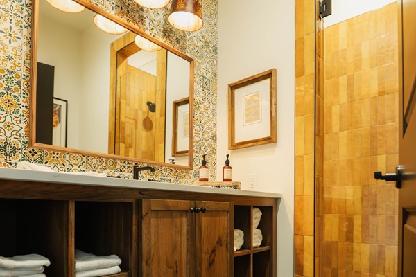 Custom vanity and cabinet detail at the Lazy Spur Suite &mdash; folded towels, designer fixtures, and Hill Country tile in a private en-suite bath.
