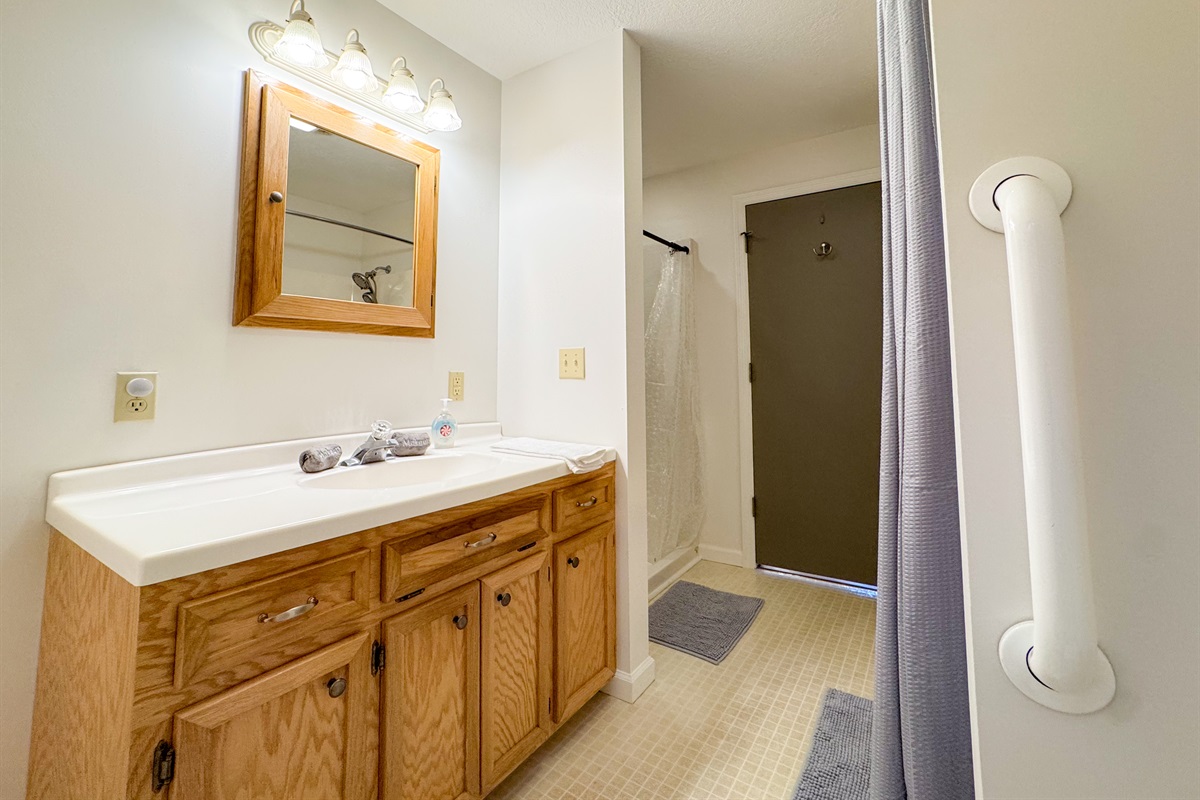 The ensuite bathroom features a tub/shower combination, toilet, vanity, grab bars, and a separate stall shower with low clearance! A rare treat!