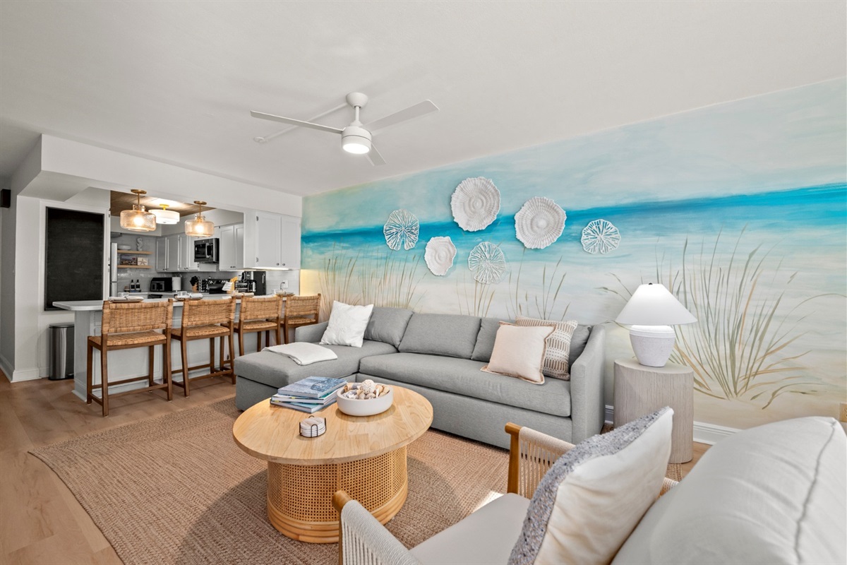 Sink into the plush sectional beneath a coastal mural, where beachy textures and soft light invite you to relax and linger after sunset.