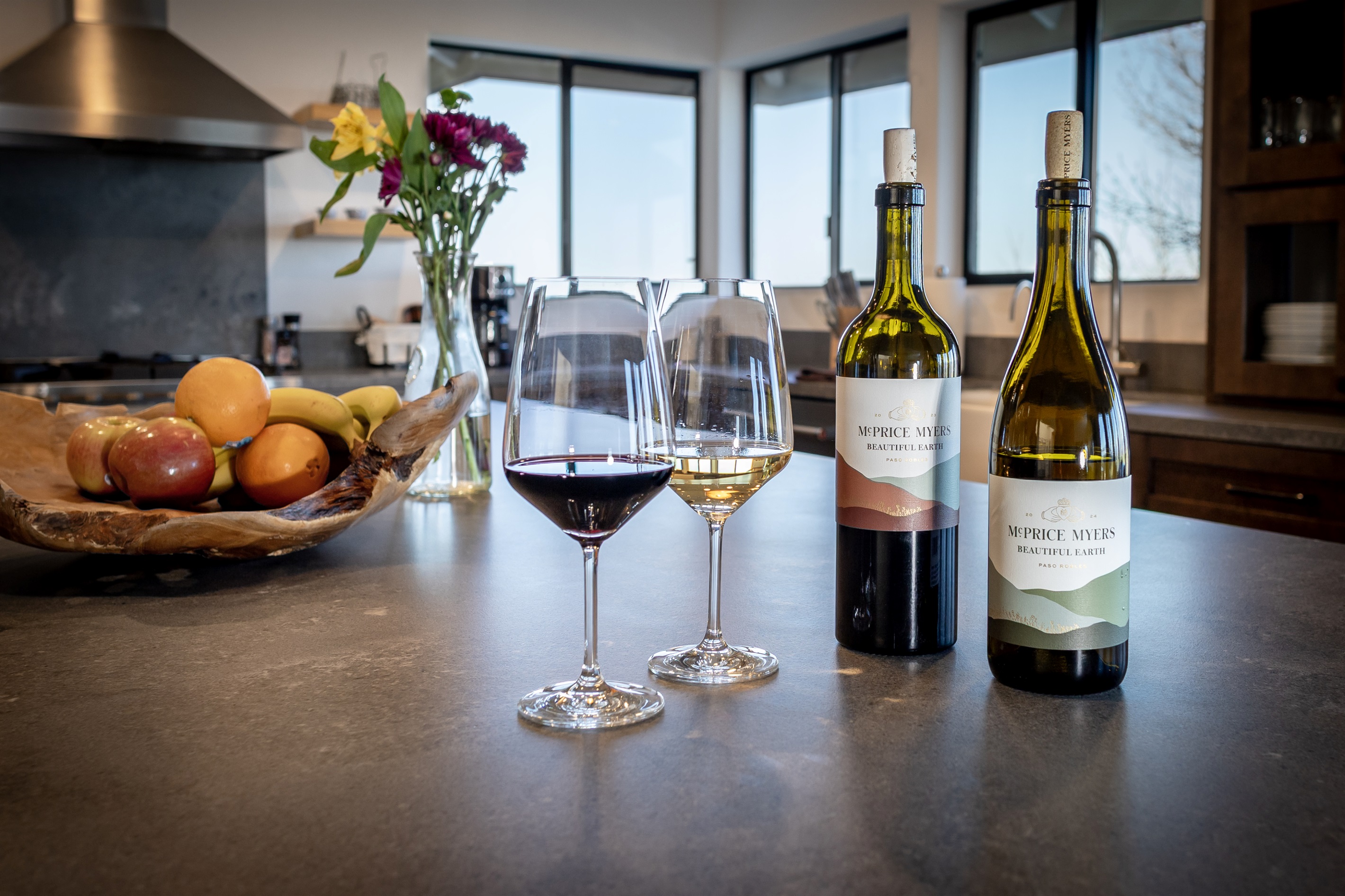 The perfect start to any evening on the hilltop — McPrice Myers Beautiful Earth red and white, wine glasses, and a kitchen made for lingering.