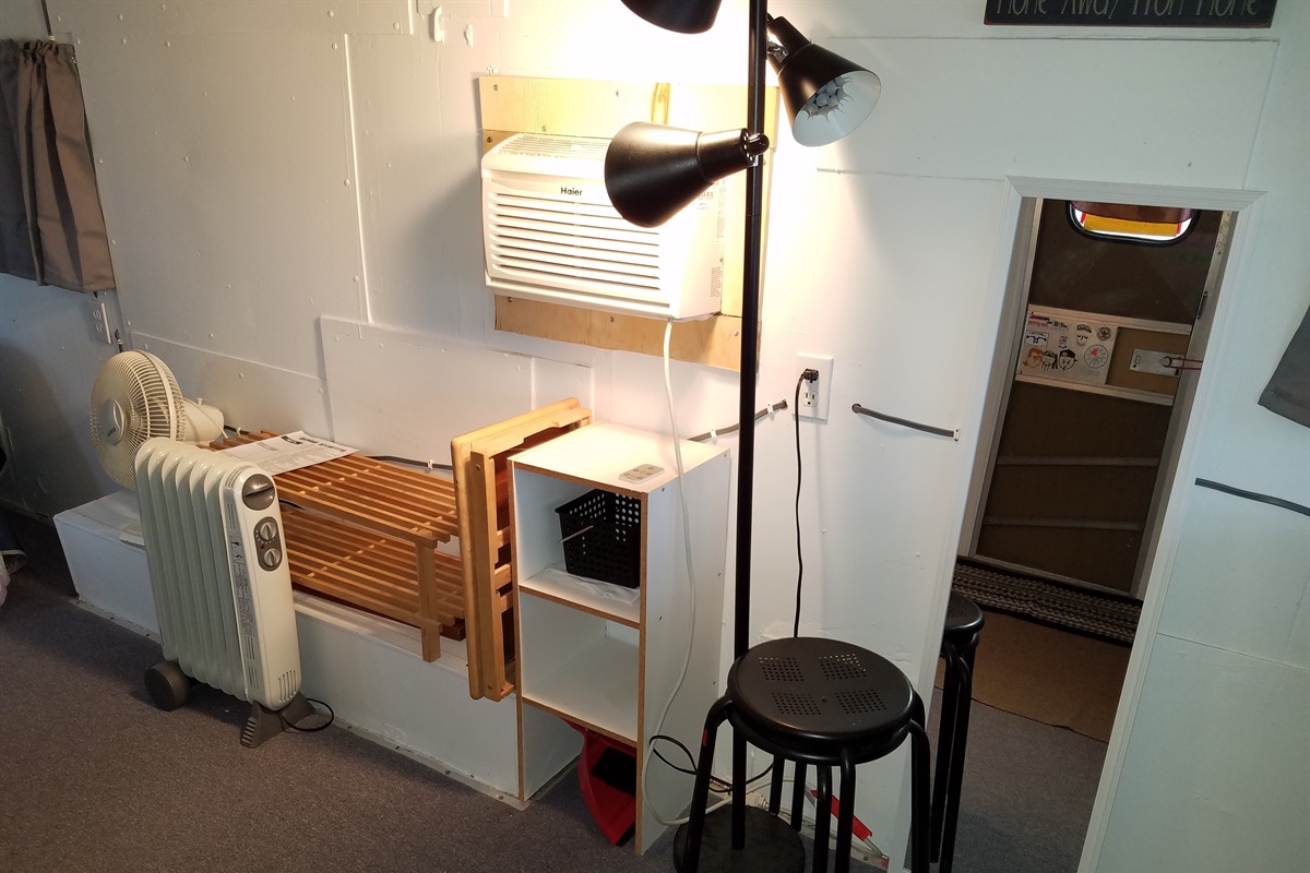 Amenities include Free WIFI, electric, AC, an electric heater, two tray tables, two sitting stools and a fan.