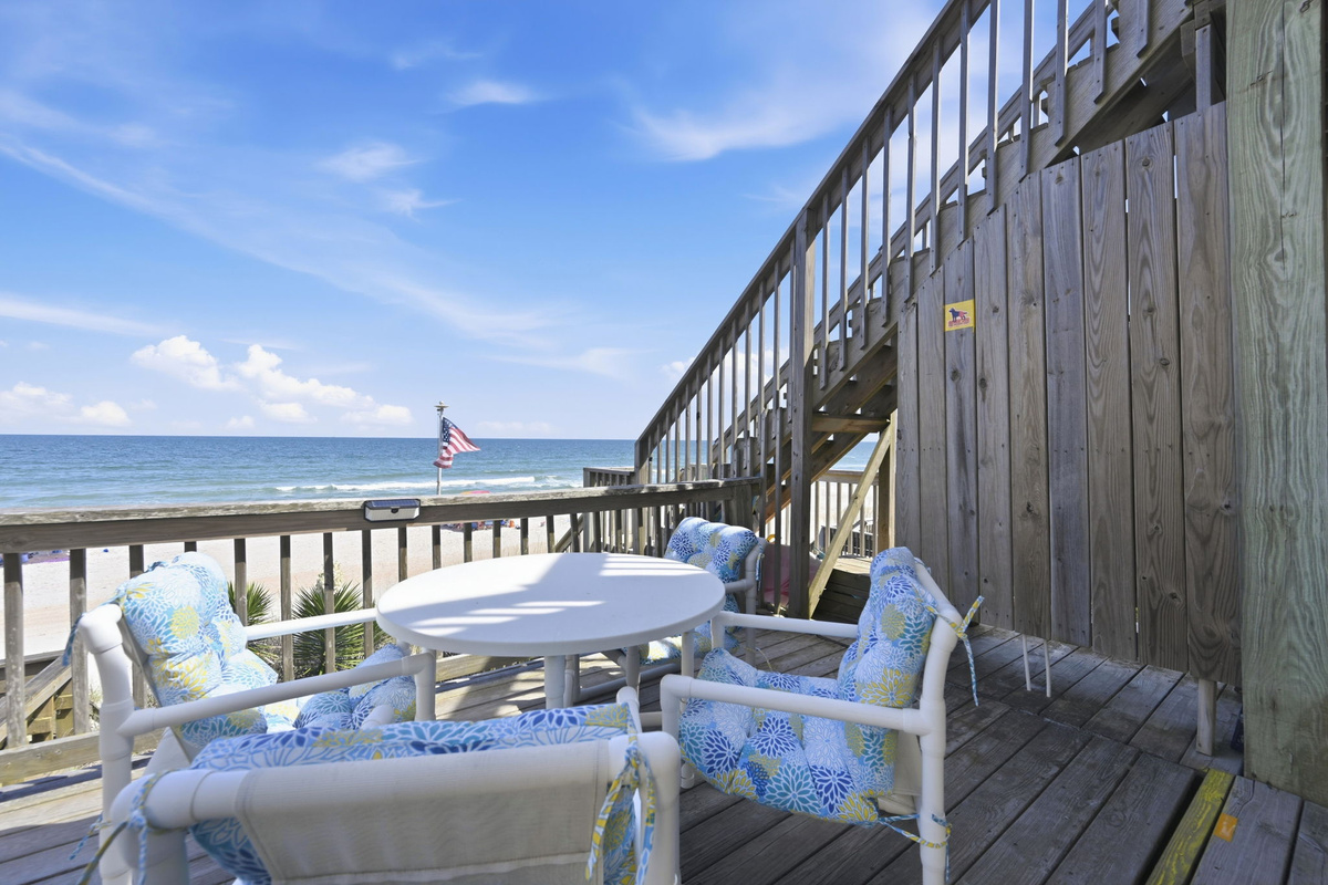 Oceanfront deck seating area with round table and panoramic beach views