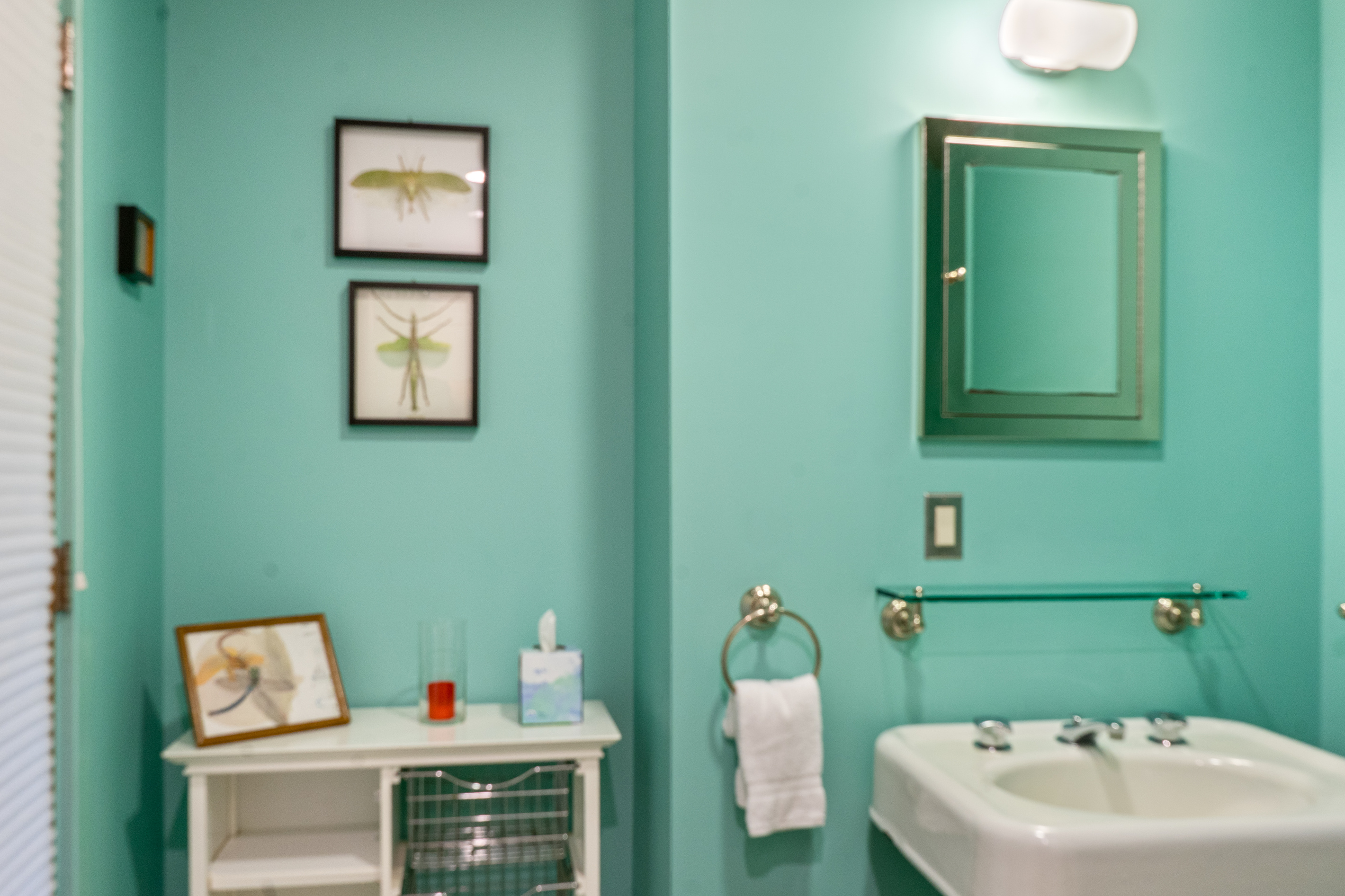 Lower-level bathroom featuring a classic pedestal sink and ample storage for fresh linens. The modern door with integrated built-in blinds ensures total privacy while maintaining the home’s clean, functional aesthetic.