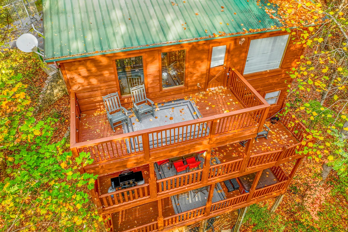 Surrounded by fall foliage, this cabin boasts multiple decks with scenic views. Rocking chairs, a hot tub, and plenty of outdoor seating create a peaceful haven in the forest.