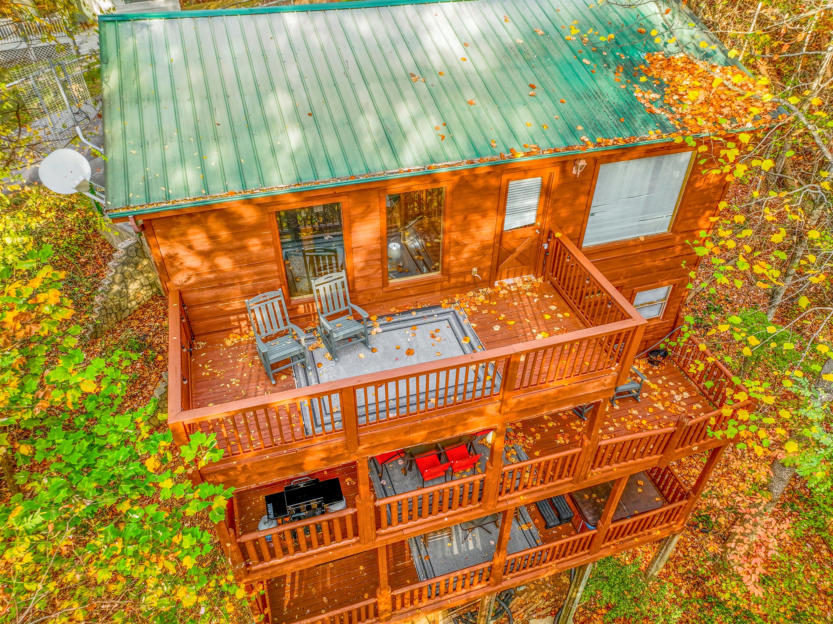 Surrounded by fall foliage, this cabin boasts multiple decks with scenic views. Rocking chairs, a hot tub, and plenty of outdoor seating create a peaceful haven in the forest.