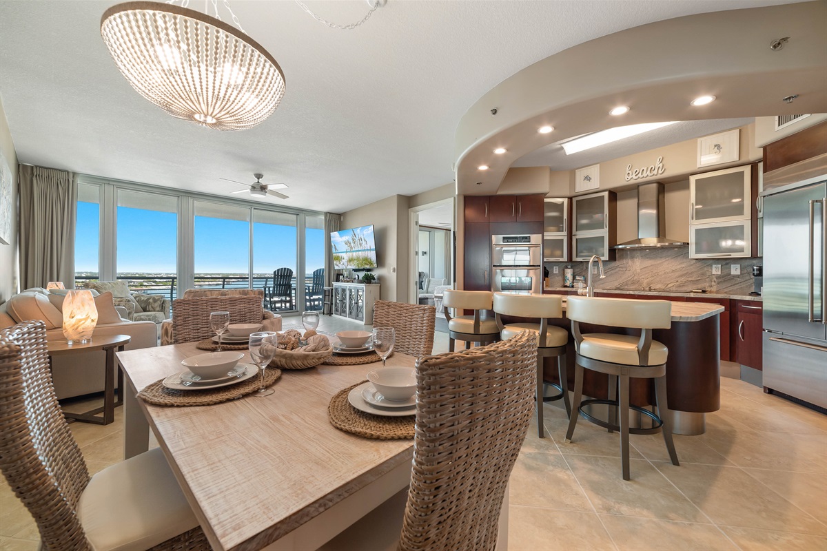 Gather around the beautifully appointed dining table, where every detail, from the textured placemats to the delicate glassware and serene colored plates, creates an inviting atmosphere for memorable meals.