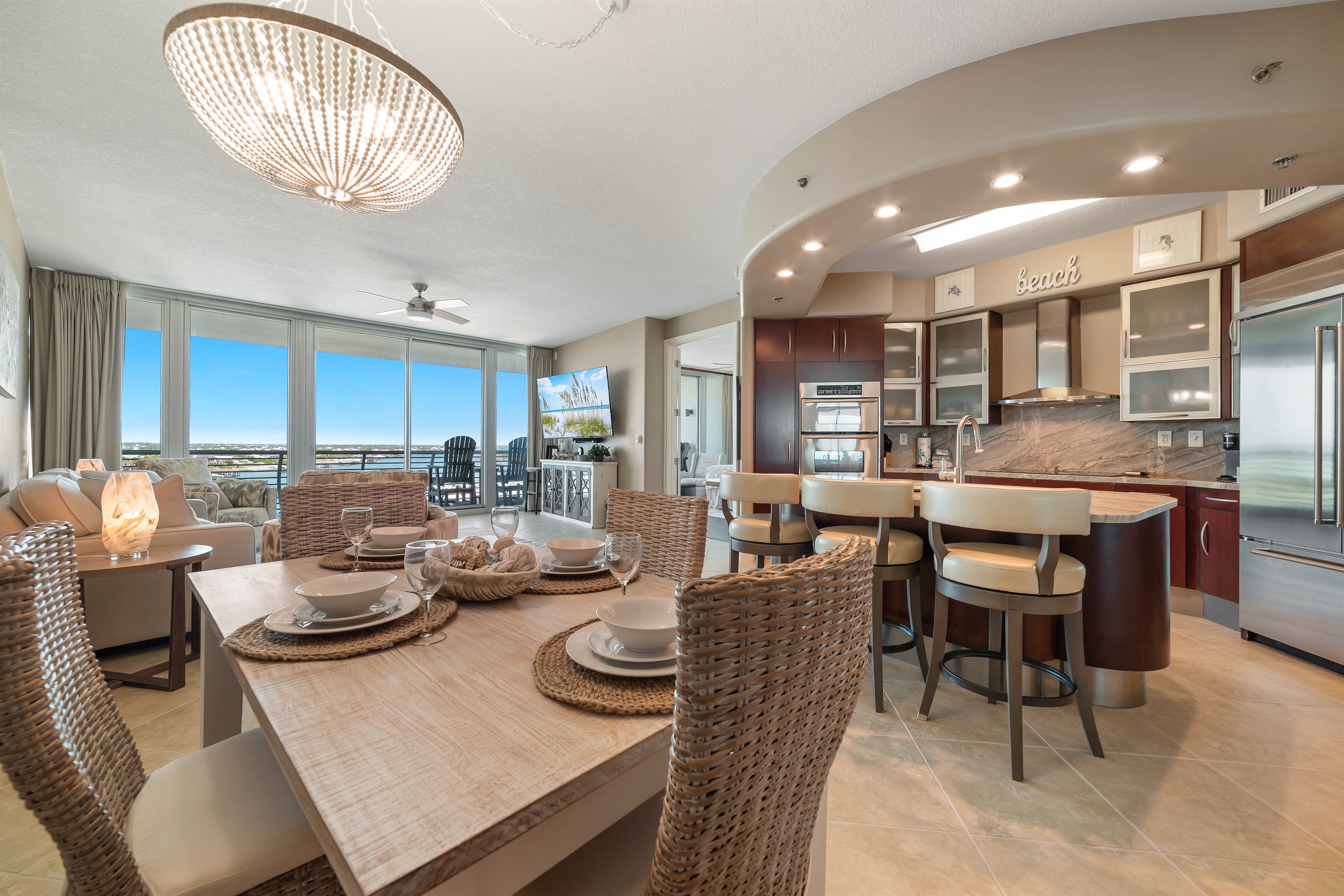 Gather around the beautifully appointed dining table, where every detail, from the textured placemats to the delicate glassware and serene colored plates, creates an inviting atmosphere for memorable meals.