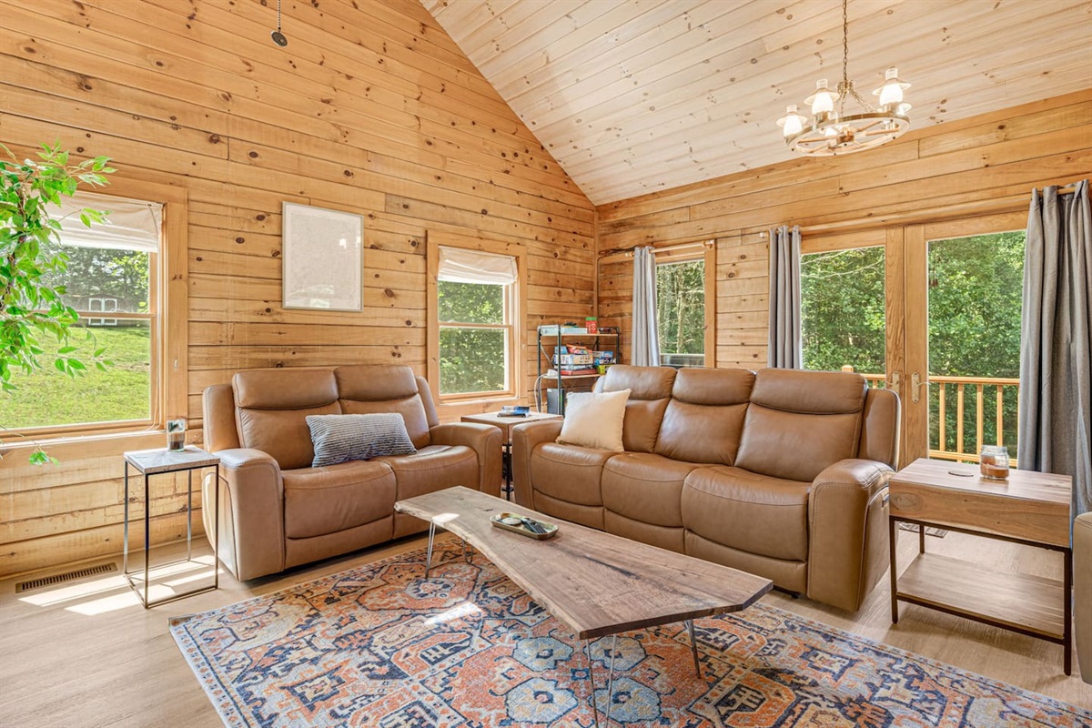 This living room invites you to relax by the stone fireplace, stretch out on soft leather seating, and soak in the beauty of nature through expansive windows. The perfect place to recharge after a day of adventure!
