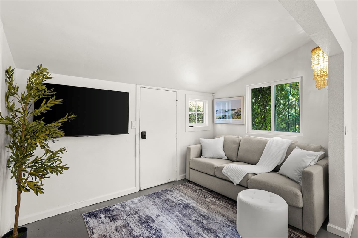 Cozy studio living space with modern decor, natural light, comfortable seating, and a Smart TV for relaxing stays. There is also a sofa bed that pull out into a queen bed. 