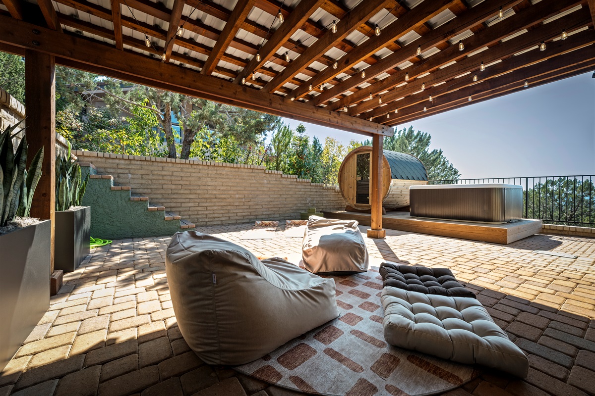 Outdoor retreat featuring a hot tub, barrel sauna, and cozy lounge area.