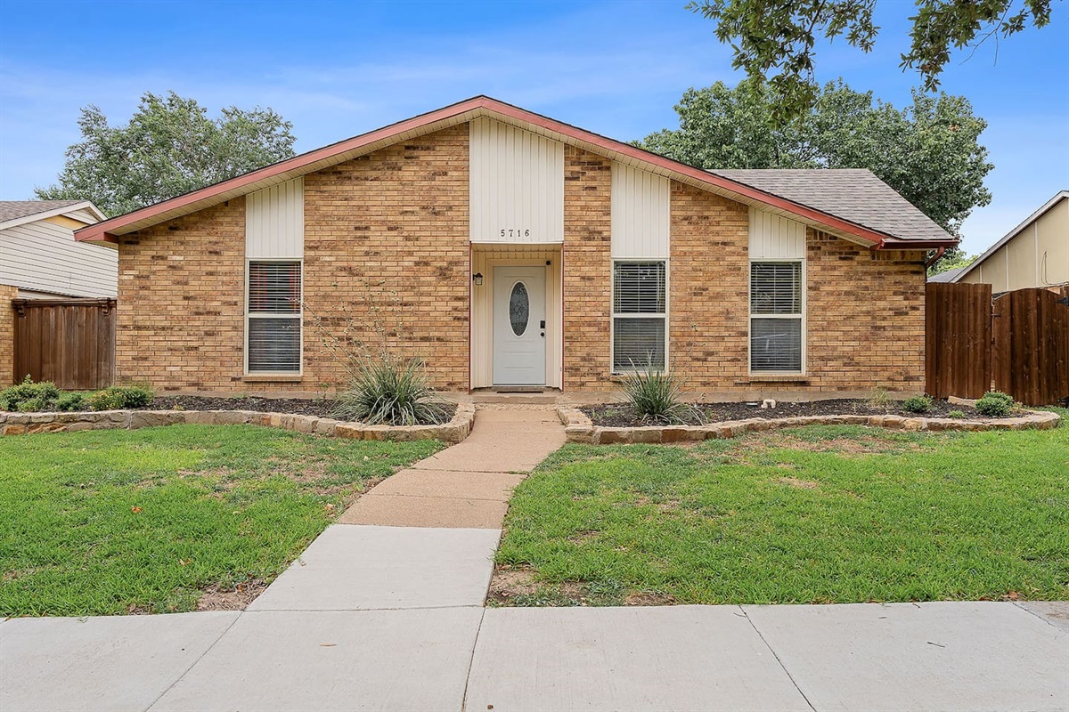 Admire the inviting facade of this brick home, complete with a neatly manicured garden and a cozy front entrance.