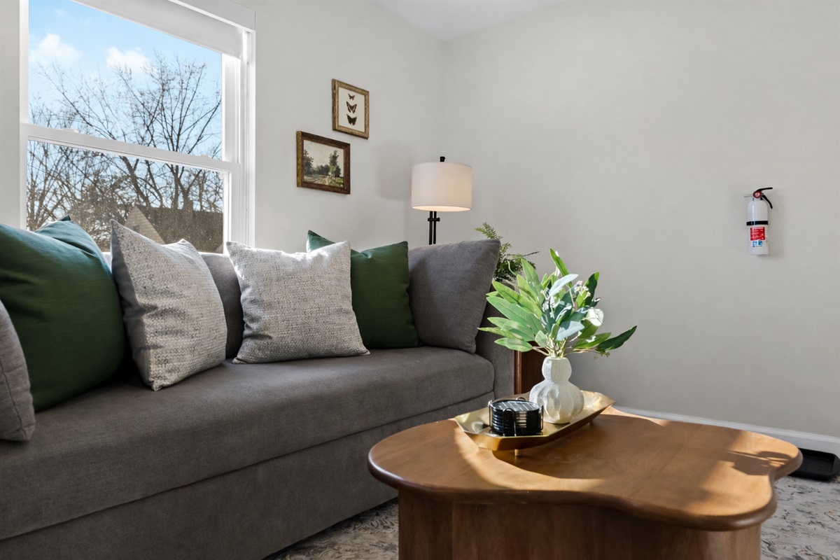 Cozy seating bathed in natural light, accented with warm textures and greenery—an inviting spot to relax, read, or enjoy a peaceful moment.
