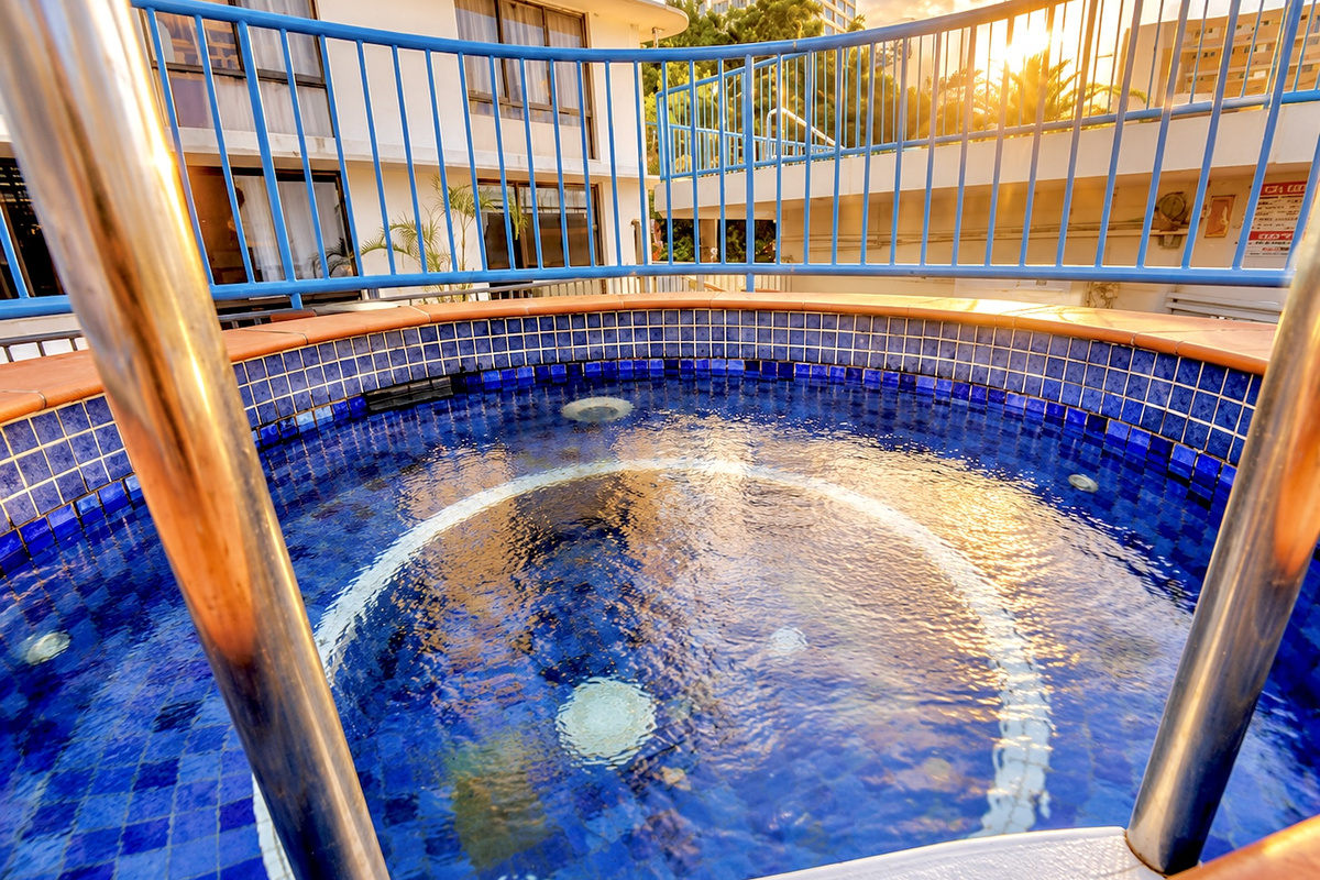 This shared spa sits beside the pool area, with tiled seating, handrails and open-air surrounds within the building’s recreation facilities.