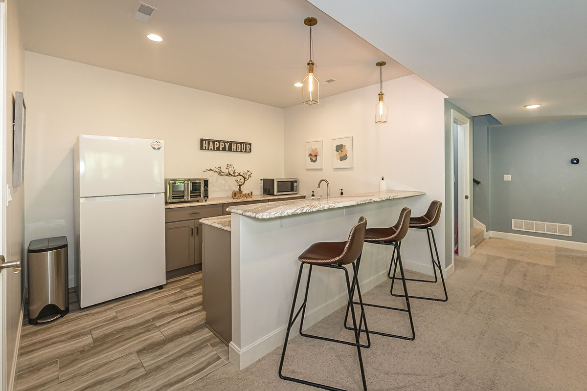 Lower-level kitchenette with refrigerator, microwave, air fryer, sink, and bar seating.