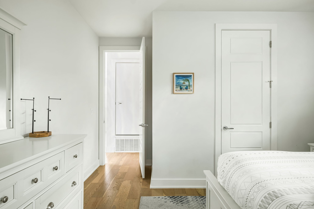 Well-appointed guest room with a stylish dresser, decorative accents, and a bright hallway leading to the rest of the home.