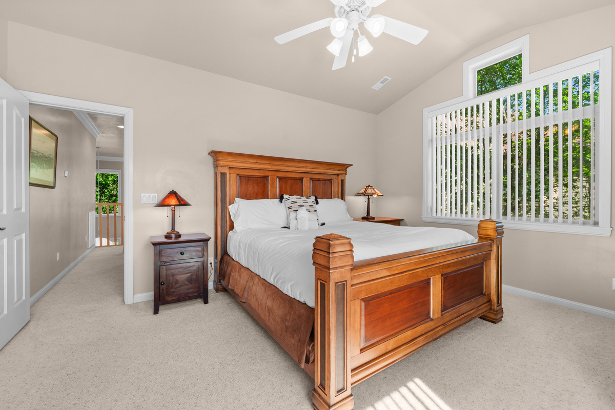 This spacious and serene bedroom features vaulted ceilings, oversized windows, and beautiful wood furnishings, creating the perfect place to relax and recharge after a day exploring Ogden Valley.