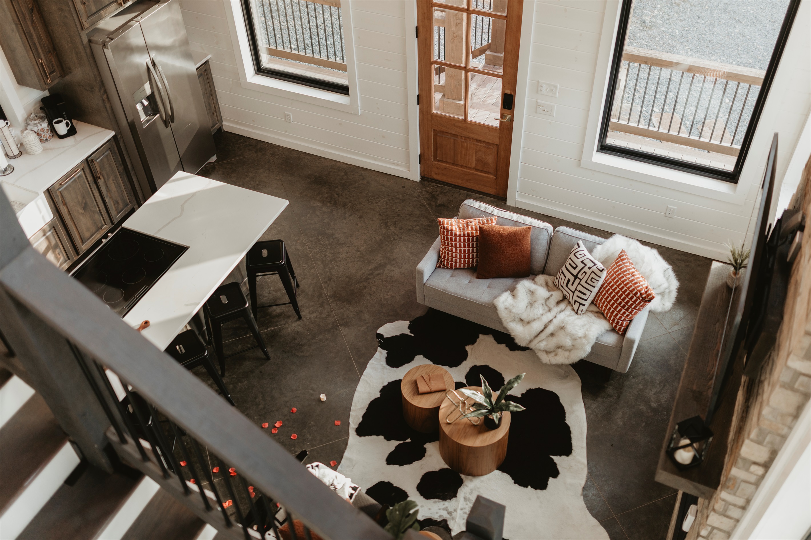 An open-concept living space with soaring ceilings, a cozy sofa, and a modern fireplace. Natural light and forest views create the perfect backdrop for gathering, relaxing, and enjoying cabin life together.