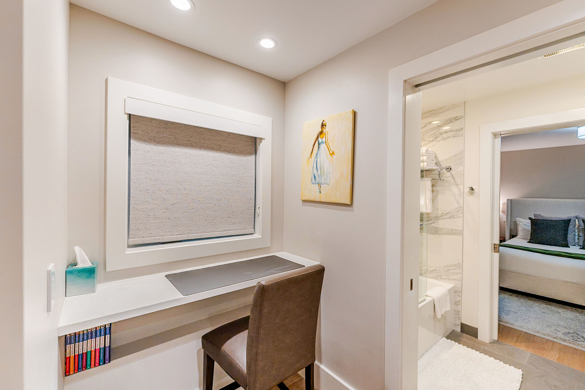 Built-in desk workspace with power and USB outlets, leather stool, desk mat and book shelf below.