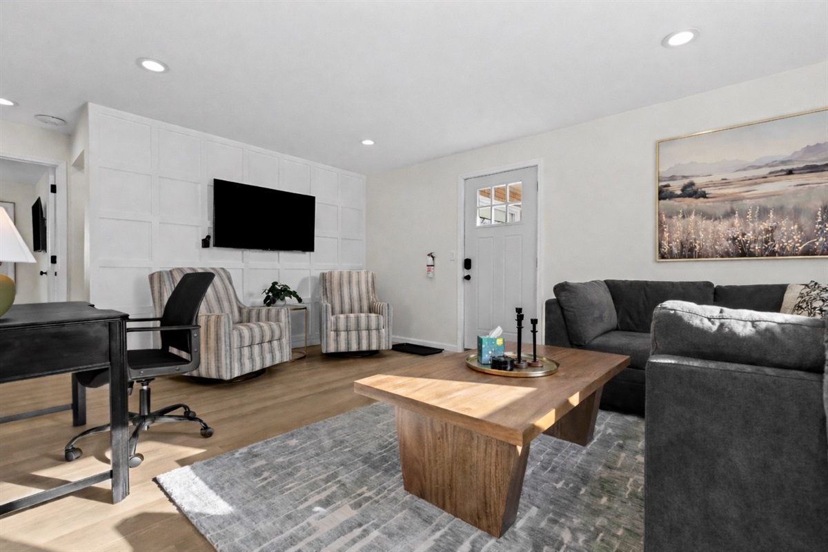 Relax in this sun-filled living room featuring plush seating, a smart TV, and a dedicated workspace—designed for comfort, productivity, and easy unwinding.