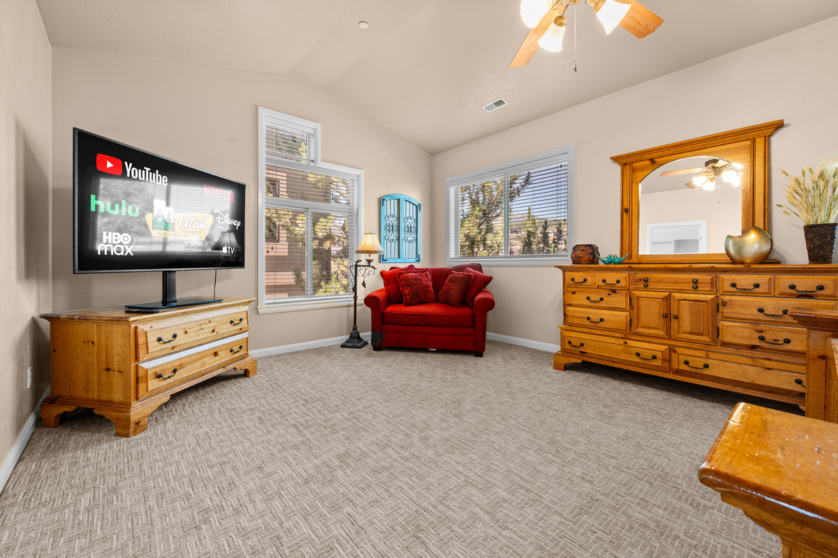 Unwind with a movie in the spacious primary suite featuring comfortable seating and large windows.