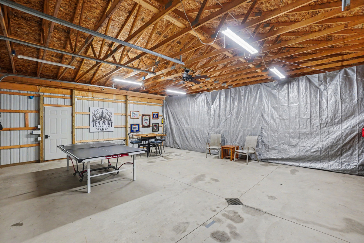 Garage game room with ping pong table, darts, tv and table and chairs.
