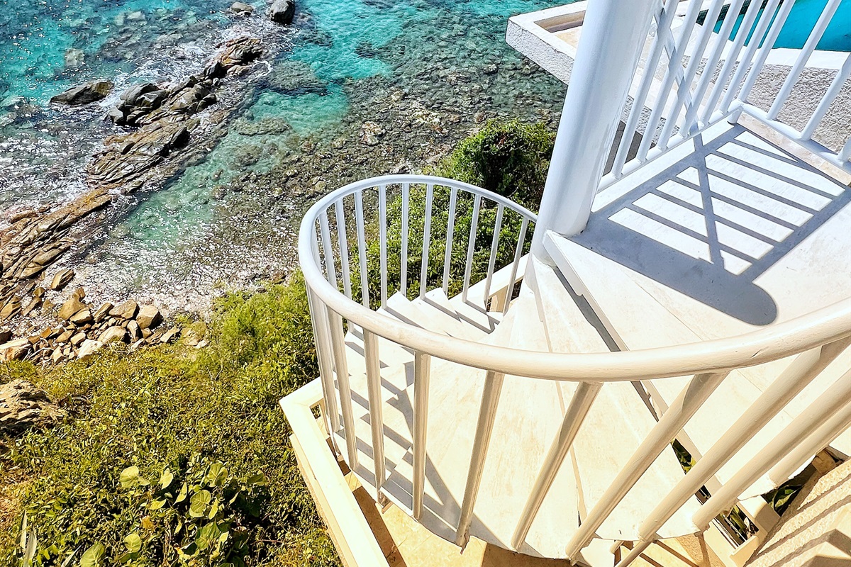 The spiral staircase by the pool that leads to the two bedrooms on the lower leverl, one is an apartment and the other is a bedroom with an ensuite bathroom.