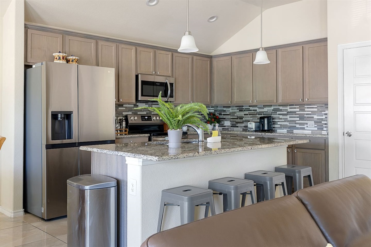 Welcome to a modern kitchen featuring stainless steel appliances, sleek cabinetry, and a spacious island with barstool seating for casual meals.