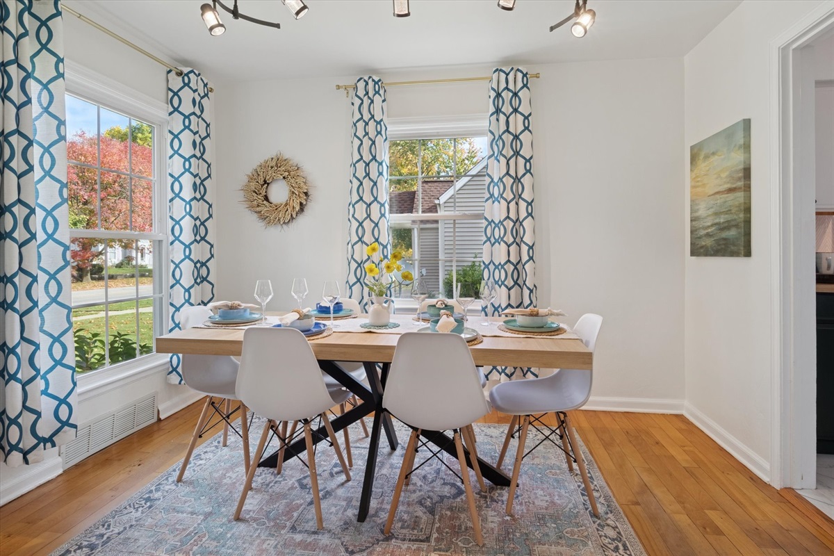 Fresh and inviting—sleek chairs and warm hardwood floors frame a dining table set with beautiful dishes. Near Notre Dame, our South Bend retreat blends style and comfort.