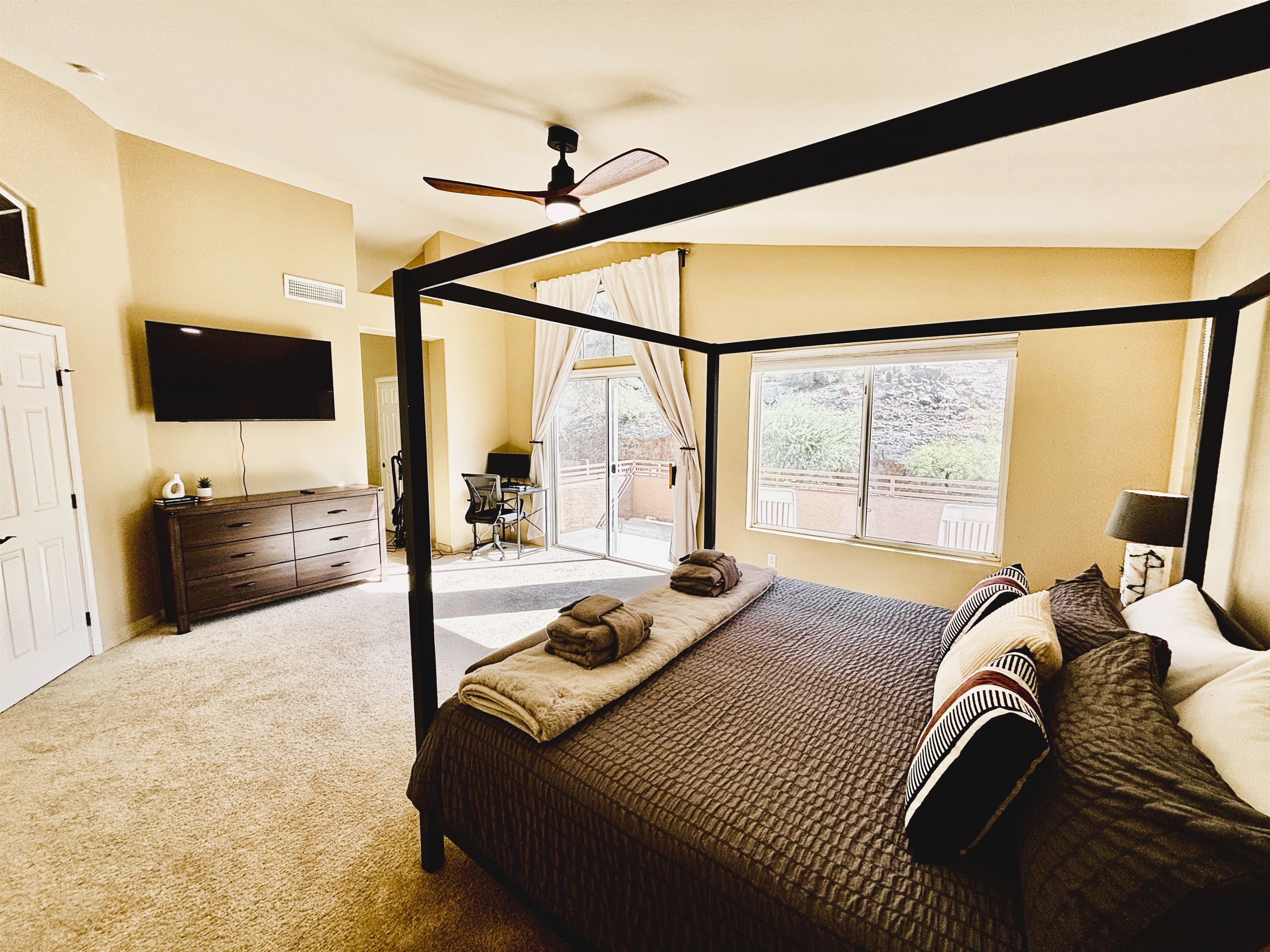 Primary bedroom with ensuite bathroom, Smart TV, walk in closet, private balcony, ceiling fan, linens and remote workstation