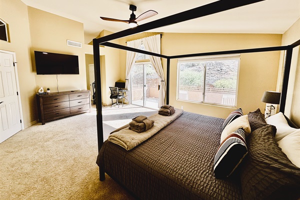 Primary bedroom with ensuite bathroom, Smart TV, walk in closet, private balcony, ceiling fan, linens and remote workstation