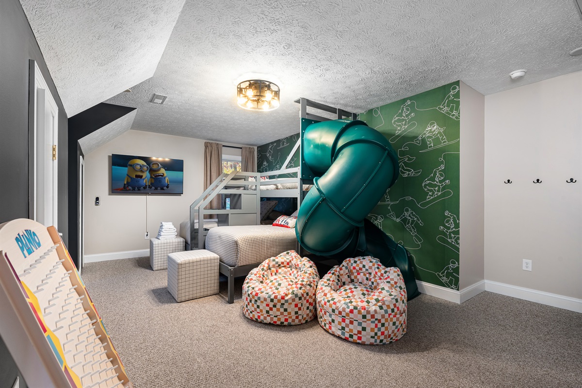 Double bunk setup with TV and playful snow-sport mural, designed for fun sleepovers.