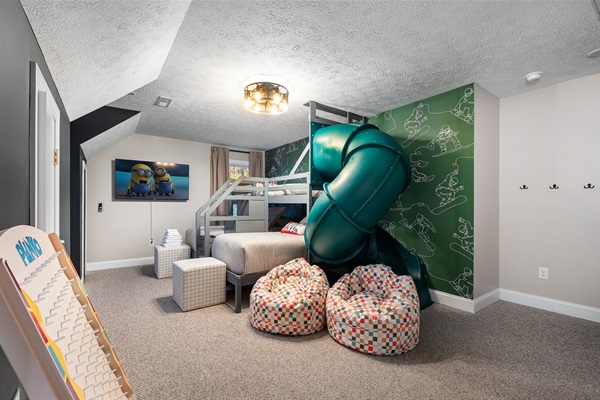 Double bunk setup with TV and playful snow-sport mural, designed for fun sleepovers.